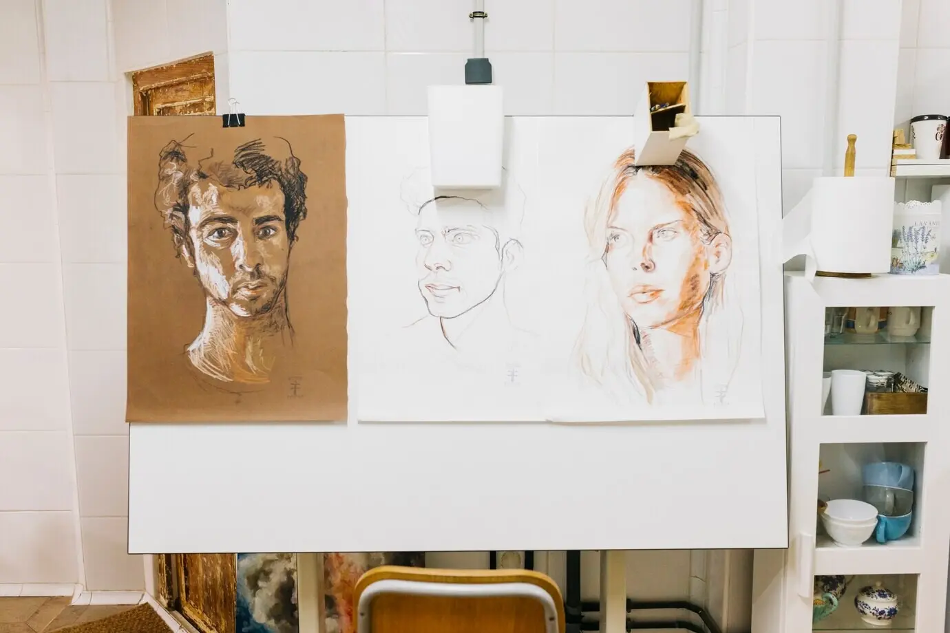 An einer Staffelei hängende Porträts von Menschen